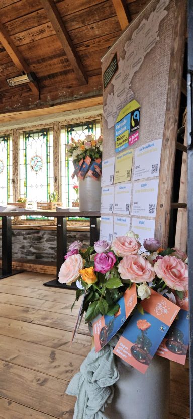 Bunte Blumen und Informationsblätter in einem hellen, rustikalen Raum.