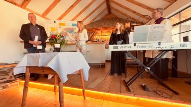 Ein kleiner Empfang mit Musikern, Blumenarrangement und Personen im Gespräch.